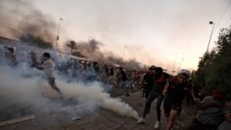 Sejumlah demonstran tampak berlarian saat petugas keamanan Irak berusaha membubarkan massa dengan menembakkan gas air mata dalam aksi protes antipemerintah di Baghdad, Irak, pada 5 Oktober 2019. (Foto: Reuters/Thaier Al-Sudani) 