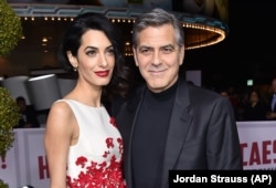 In this Feb. 1, 2016 file photo, power couple Amal and George Clooney arrive at the world premiere of "Hail, Caesar!" in Los Angeles. They are successful in two very different industries. (Photo by Jordan Strauss/Invision/AP, File)