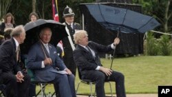 Britain&#39;s Prince Charles, center, and Prime Minister Boris Johnson, right, shelter from rain during the unveiling of the UK Police Memorial at the National Memorial Arboretum at Alrewas, England.