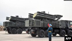 সিরিয়ার লতাকিয়া শহরের দক্ষিণ পূর্বে রুশ সামরিক ঘাঁটিতে বিজয় দিবসের সামরিক কুচকাওয়াজ চলাকালে প্যান্টসির- এস এসএ-২২ আকাশ প্রতিরক্ষা ব্যবস্থার পাশে আনুষ্ঠানিক ইউনিফর্ম পরিহিত রাশিয়ার সেনা দাড়িয়ে আছে। ফাইল ফটো। 