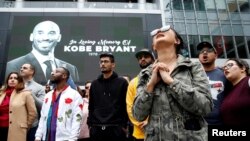 Para pengunjung berkumpul di depan foto Kobe Bryant yang dipasang di layar lebar di luar Staples Center setelah mantan pebasket klub Los Angeles Lakers tewas dalam kecelakaan helikopter, di Los Angeles, California, 26 Januari 2020. 