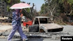 A woman walks past a burnt vehicle near Rabaa al-Adawiya mosque in Cairo, Aug. 28, 2013. 