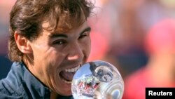 Rafael Nadal y su tradicional mordida al trofeo de campeón, tras ganar en Montreal, tras vencer a Milos Raonic de Canadá.