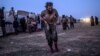 A man suspected of belonging to the Islamic State group walks past members of the Kurdish-led Syrian Democratic Forces just after leaving IS' last holdout of Baghuz, in the eastern Syrian province of Deir Ezzor, March 4, 2019. 