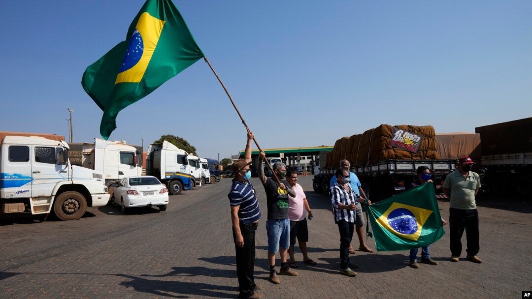Para sopir truk mengibarkan bendera saat melakukan aksi mogok untuk mendukung pemerintahan Presiden Bolsonaro di Brasilia, Brazil, Kamis (9/9). 