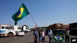 Truck drivers supporting Brazilian President Jair Bolsonaro wave flags as they gather at a gas station just south of Brasilia, Brazil, Sept. 9, 2021. 