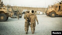 Un soldat américain du 3e régiment de cavalerie marche avec l'interprète afghan de l'unité avant une mission près de la base d'opérations avancée Gamberi dans la province de Laghman en Afghanistan, le 11 décembre 2014.