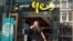 FILE - A woman uses her mobile phone as she walks past in front of an Optus shop in Sydney, Australia, Feb. 8, 2018. 