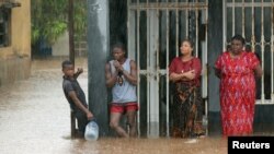 Warga berdiri di luar sebuah rumah yang dilanda banjir akibat hujan setelah Topan Kenneth melanda di Pemba, Mozambik, 28 April 2019.
