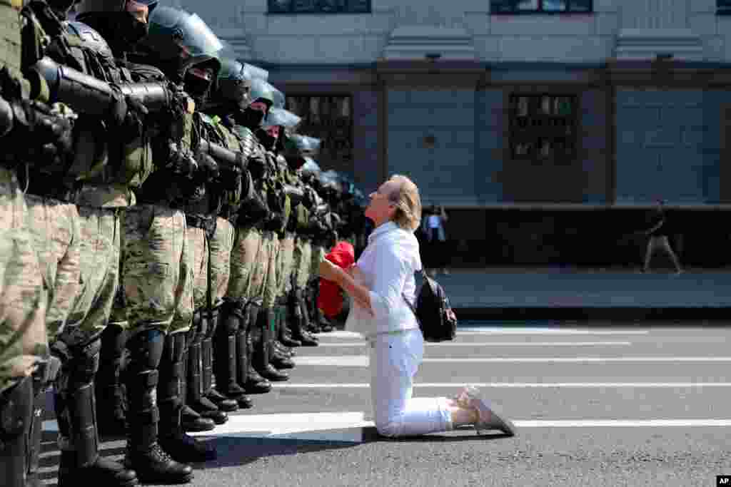 A woman kneels in front of a riot police line as they block Belarusian opposition supporters rally in the center of Minsk, Belarus.