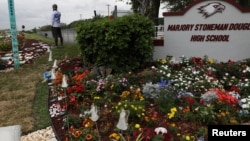 Uno de los sobrevivientes de la matanza de Parkland, Chad Williams, de 19 años, junto al jardín conmemorativo creado en la escuela secundaria Marjory Stoneman Douglas.