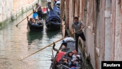 FILE - Tourists enjoy a gondola ride in Venice, Italy, May 16, 2021. The European Union is looking to allow its member countries to welcome fully vaccinated visitors from outside the bloc. 