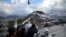 FILE - Tourists take photos of the Potala Palace beneath a security camera in Lhasa, capital of the Tibet Autonomous Region of China, Sept. 19, 2015. 