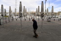 FILE - A man wearing a face mask walks past the closed terrace of a restaurant near Le Vieux Port in Marseille, southern France, on Sept. 28, 2020.