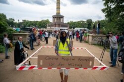 FILE - A protestor with a social distancing barrier, takes part in a demonstration against COVID-19 measures, in Berlin, Sept. 1, 20202. Sign reads 'Corona Hygiene Concept for everyday life.'