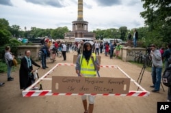 FILE - A protestor with a social distancing barrier, takes part in a demonstration against COVID-19 measures, in Berlin, Sept. 1, 20202. Sign reads 'Corona Hygiene Concept for everyday life.'