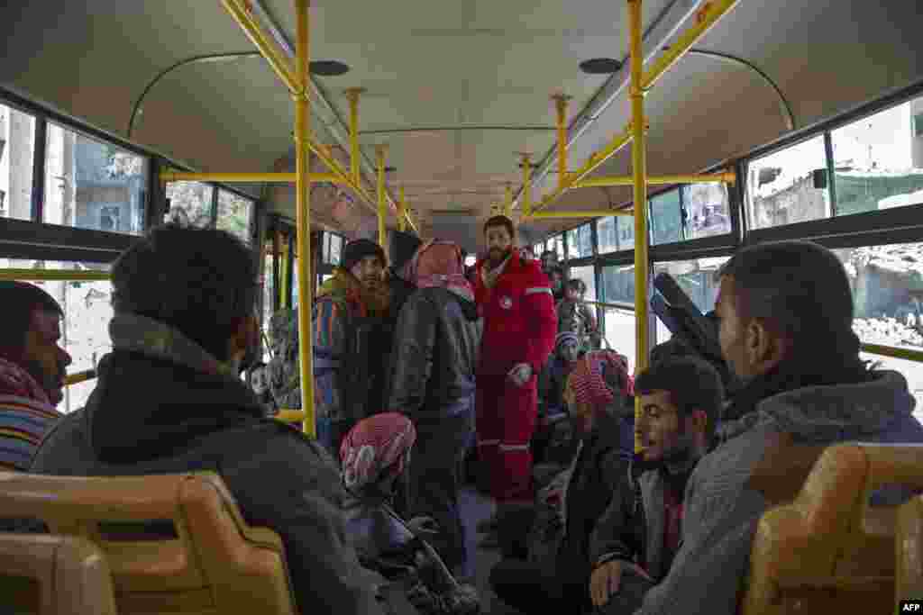 Staf Palang Merah Suriah berdiri di dalam bus di tengah pemberontak dan keluarganya dalam operasi evakuasi di Aleppo (15/12). (AFP/Karam Al-Masri)