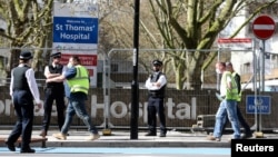 Police officers and building workers are seen outside St Thomas' Hospital in London after British Prime Minister Boris Johnson was admitted with persistent coronavirus (COVID-19) symptoms, London, April 6, 2020. 