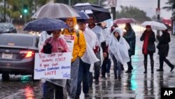 Maestros de Los Angeles protestan bajo la lluvia frente a una secundaria que lleva el nombre de la ciudad durante una huelga de educadores el 14 de enero de 2019. 