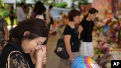 Sarah Kee, 61, of Singapore, wipes her tears at an area set aside for tributes to former Singapore Prime Minister Lee Kuan Yew at the hospital where he passed away, Monday, March 23, 2015 in Singapore. Kee remembers waving to Lee's motorcade daily as it p