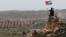 A protester waves a Palestinian flag in front of the Jewish settlement of Ofra during clashes near the West Bank village of Deir Jarir near Ramallah Apr. 26, 2013.