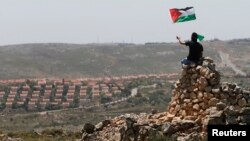 Seorang demonstran melambaikan bendera Palestina di dekat permukiman Yahudi Ofra di dekat Ramallah, Tepi Barat (foto: dok). Liga Arab mengusulkan pertukaran lahan untuk sengketa perbatasan Israel-Palestina. 