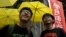 Student leaders Joshua Wong (R) and Nathan Law smile in front of supporters holding yellow umbrellas, symbol of the Occupy Central movement, outside a police station in Hong Kong, July 14, 2015.