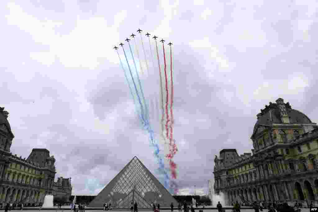 Nine alphajets from the French Air Force Patrouille de France release trails of blue, white and red smoke, colors of French national flag, as they fly over Louvre museum and the Louvre Pyramid during the Bastille Day military parade in Paris, on July 14, 