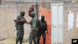 Soldiers stand outside a vacant lot and the site of a mass grave in Durango, May 10, 2011