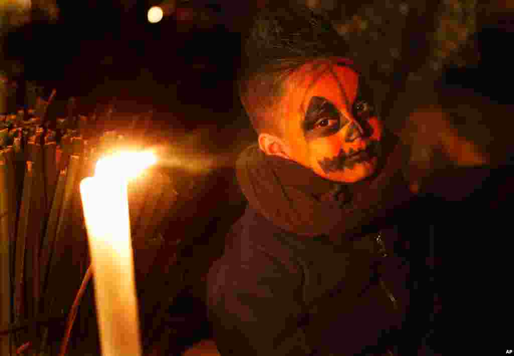A child sits next to a tomb illuminated with candles in the San Gregorio Atlapulco cemetery during Day of the Dead festivities on the outskirts of Mexico City.
