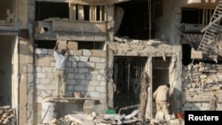 FILE - A man rebuilds a wall of a damaged building in the rebel held al-Katerji district in Aleppo, Syria, Aug. 13, 2016.