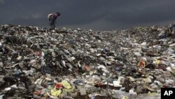 A woman searches for reusable material at a garbage dump near Deepor Beel Wildlife Sanctuary on the outskirts of Gauhati, India, June 5, 2012.