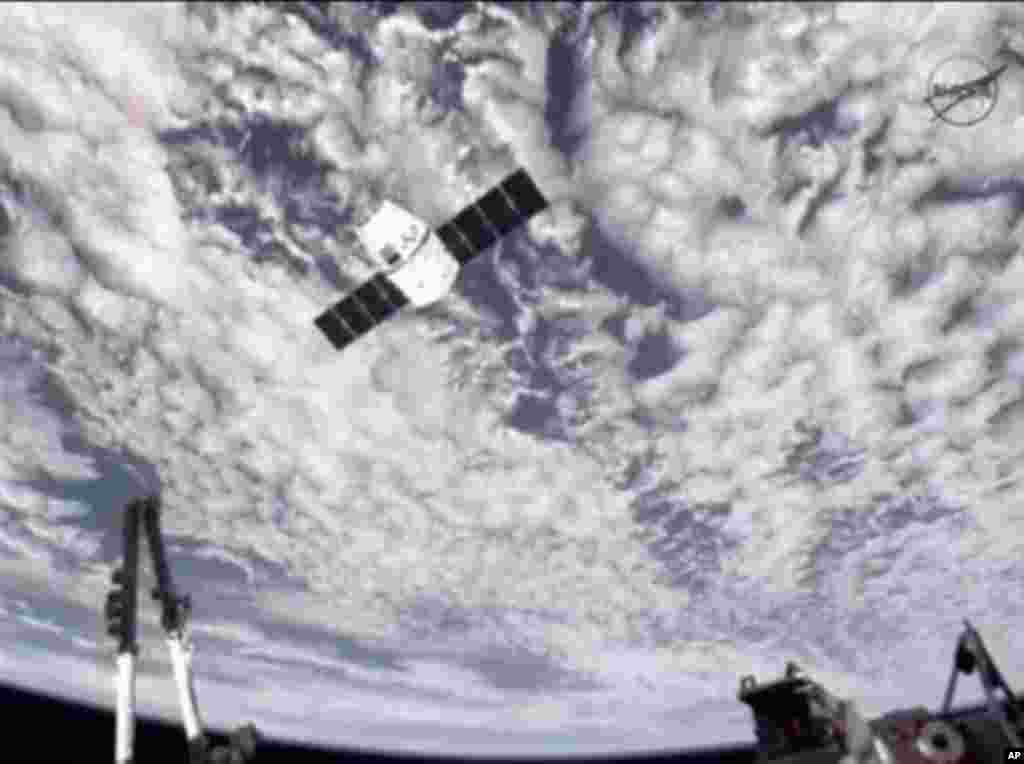 This image provided by NASA-TV shows the SpaceX Dragon commercial cargo craft, top, as Dragon approaches the International Space Station, Friday, May 25, 2012. Dragon is scheduled to spend about a week docked with the station before returning to Earth on 