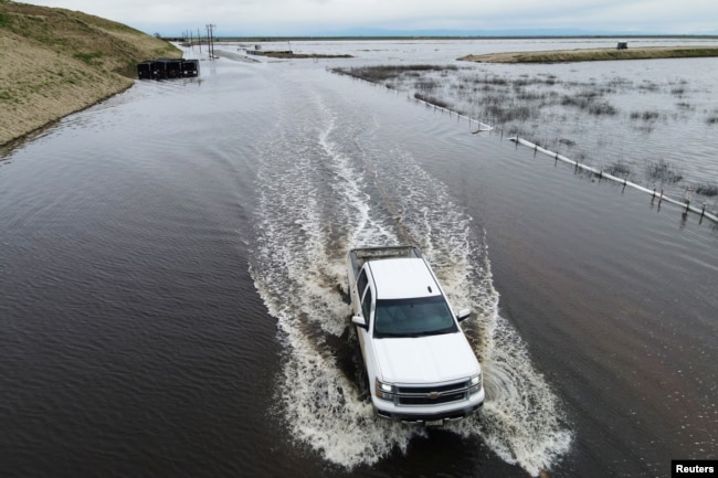 A truck passes on a road as floodwaters from the Tule River inundate the area after days of heavy rain in Corcoran, California, U.S. on March 22, 2023. (REUTERS/David Swanson)