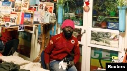 Samuel Pieta, 33, holds his cat in his apartment room in one of the four occupied buildings by migrants of the former Olympic village in Turin, Italy, Jan. 8, 2018. 