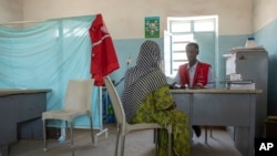 FILE - A Tigrayan woman who says she was gang raped by Amhara fighters, speaks to surgeon and doctor-turned-refugee, Dr. Tewodros Tefera, at the Sudanese Red Crescent clinic in Hamdayet near the Sudan-Ethiopia border, eastern Sudan, March 23, 2021. 