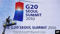 A worker adjusts a giant banner at the entrance to the G-20 Summit in Seoul, South Korea (file photo)