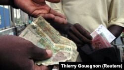 FILE — People exchanging CFA franc banknotes for new ones in the closing hours of a region-wide changeover.