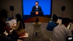 FILE - Journalists work on laptops at the China National Convention Center as Chinese President Xi Jinping delivers a statement in Beijing, May 15, 2017. China is tightening control over foreign companies' internet use.