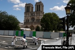 FILE - Workers protective gear after a delay prompted by fears of lead contamination clean the area in front of Notre-Dame de Paris cathedral, on Aug. 19, 2019 in Paris. (AP Photo/Francois Mori, File)