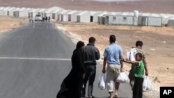A Syrian refugee family walks towards the new Syrian camp of Azraq, which stretches for 15 kilometers, and lies about 100 kilometers from the Syrian border in Jordan, Wednesday, April 30, 2014.