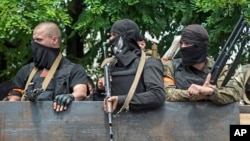 Ukrainian troops stand atop of a vehicle as they leave the scene of fighting in Mariupol, eastern Ukraine, June 13, 2014. 