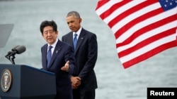 ນາຍົກລັດຖະມົນຕີຍີ່ປຸ່ນ ທ່ານ Shinzo Abe, ຊ້າຍ, ກຳລັງ ກ່າວ ໃນຂະນະທີ່ ປະທານາທິບໍດີ ສະຫະລັດ ທ່ານ Barack Obama ຫລຽວເບິ່ງ ຖານທັບ Pearl Harbor-Hickam, ລັດ Hawaii, ວັນທີ 27 ທັນວາ, 2016.