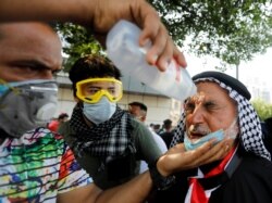 A demonstrator sprays medical fluid on the face of a man who was affected by tear gas during a protest in Baghdad, Iraq, Oct. 29, 2019.