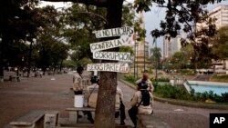 Miembros de la guardia bolivariana descansan a la sombra de un árbol con rótulos anticorrupción en Caracas.