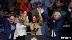 Vice President and Democratic presidential candidate Kamala Harris poses for photos with Democratic vice presidential candidate, Minnesota Gov. Tim Walz, Former U.S. Rep. Gabby Giffords, and Sen. Mark Kelly during a campaign rally, in Glendale, Arizona, Aug. 9, 2024. 