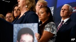 Prezidan Donald Trump ki t ap koute pandan yon rankont sou imigrasyon. Li te genyen bò kote li manm fanmi moun ki te viktim krim imigran ilegal komèt Ozetazini. (Oditoryòm Sid Mezon Blanch la, 22 jen 2018 la, nan Washington). 