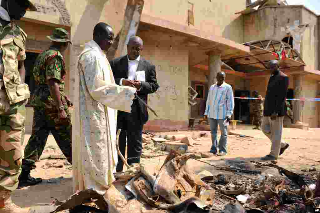 A member of the clergy guides security forces through the scene of a car bomb explosion at St. Theresa Catholic Church outside Nigeria's capital Abuja. (Reuters)