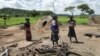 Members of a family stand next to their grass-hut dwelling which was destroyed by the police at Manzou Farm in Mazoe, north of Harare, in Zimbabwe, Jan. 15, 2015.