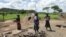 Members of a family stand next to their grass-hut dwelling which was destroyed by the police at Manzou Farm in Mazoe, north of Harare, in Zimbabwe, Jan. 15, 2015.